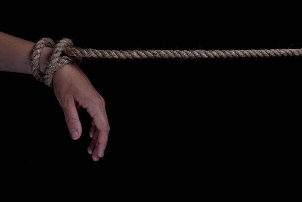 Tied hands with a rope on a black background. copy space for text - Фото, изображение