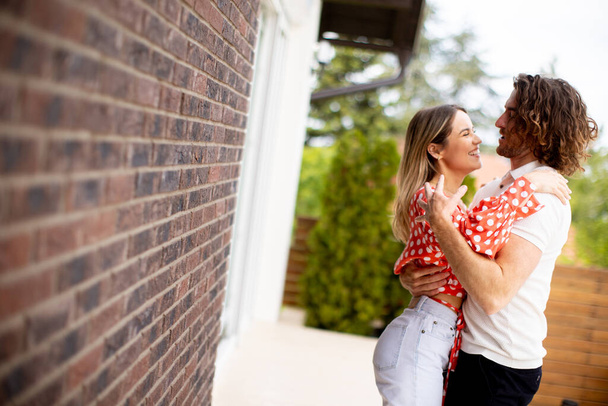 Beau jeune couple souriant amoureux devant le mur de briques de la maison - Photo, image