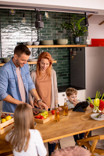 Boldog fiatal család készül zöldségek a konyhában - Fotó, kép