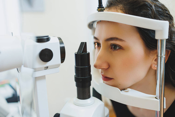 Examen de la visión en equipos oftalmológicos modernos. Examen ocular de una mujer en una cita con un oftalmólogo usando microscopios. Tratamiento de la visión en una cita con un oftalmólogo - Foto, Imagen