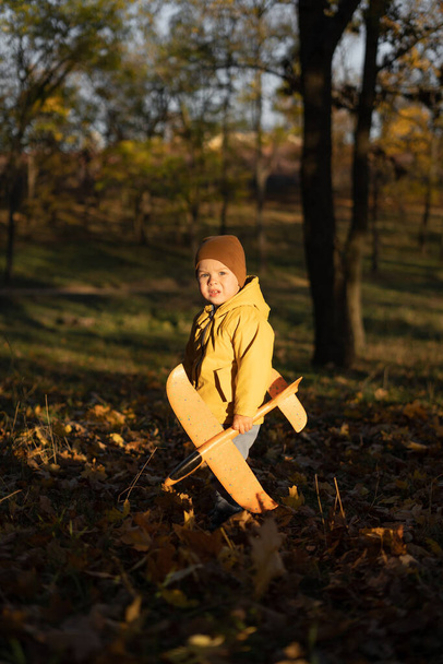 Chłopiec bawiący się samolotem w jesiennym parku. Koncepcja wolności i szczęśliwego dzieciństwa. Przestrzeń kopiowania - Zdjęcie, obraz