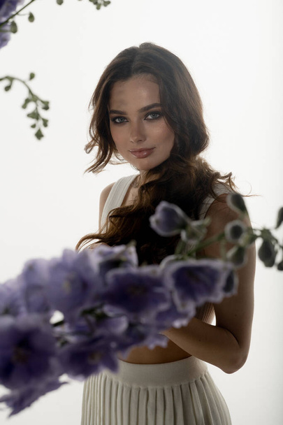 portrait of fashionable young woman posing in studio with flowers - Zdjęcie, obraz
