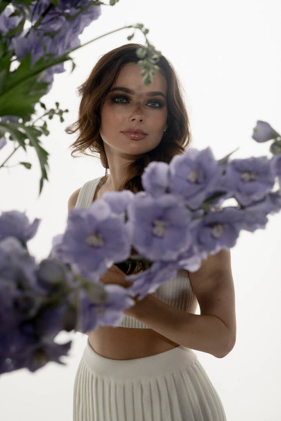 portrait of fashionable young woman posing in studio with flowers - Φωτογραφία, εικόνα