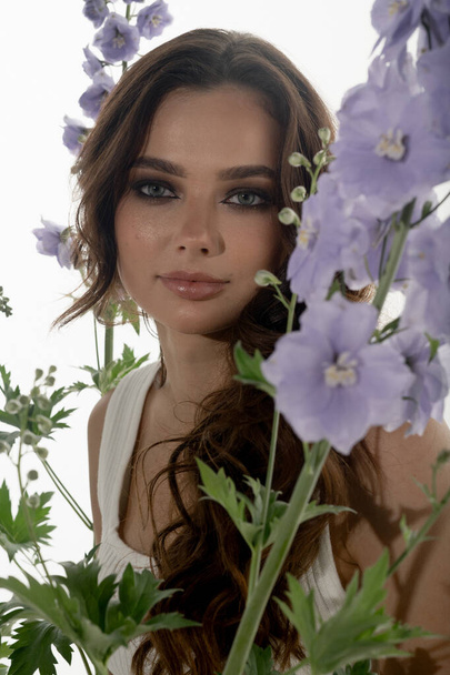 portrait of fashionable young woman posing in studio with flowers - Foto, Imagem