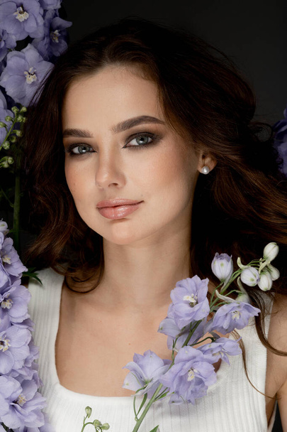 portrait of fashionable young woman posing in studio with flowers - Zdjęcie, obraz