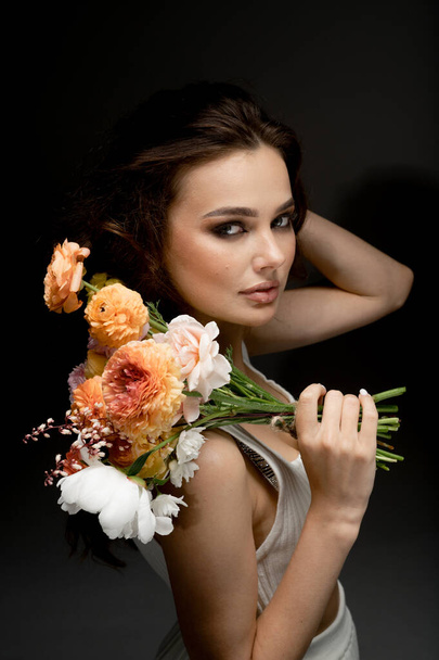portrait of fashionable young woman posing in studio with flowers - Foto, afbeelding