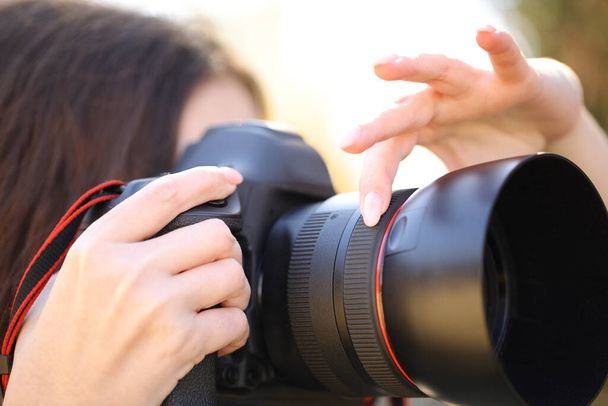Close up ritratto di un fotografo mano regolazione messa a fuoco manualmente scattare foto all'aperto - Foto, immagini