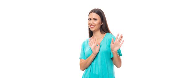 young pretty european woman with dark long hair dressed in a blue t-shirt refuses on a wide white background with copy space. - Photo, Image
