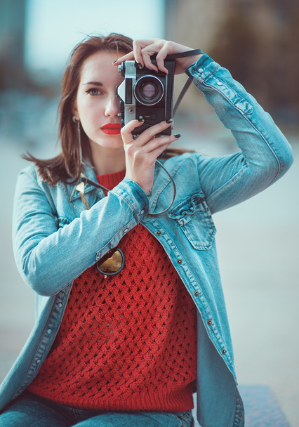 Hipster girl making picture with retro camera. Focus on camera - Photo, Image