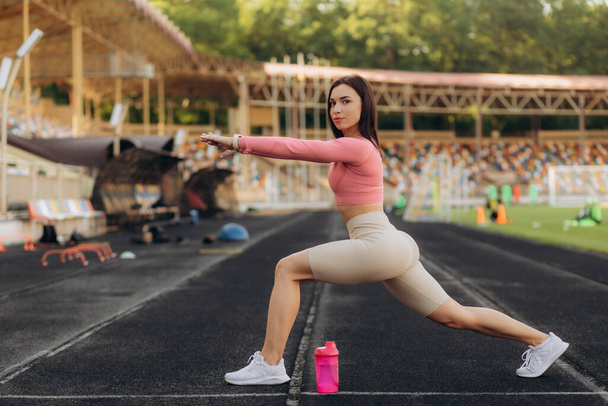 Young sportswoman doing warm up exercise on running track. - Photo, Image