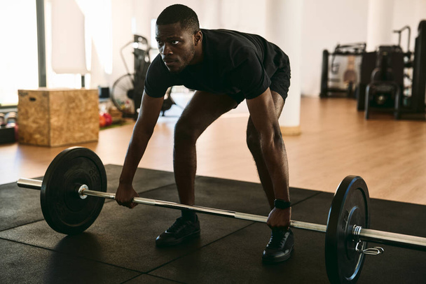 Volledige lichaam van sterke Afro-Amerikaanse sportman tillen zware lange halter tijdens het sporten in de moderne fitnessruimte tijdens intensieve training - Foto, afbeelding