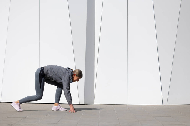 Active senior. Woman in grey sportswear exercising and looking energetic - Фото, зображення