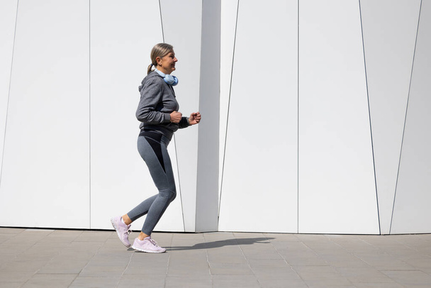 Active senior. Woman in grey sportswear exercising and looking energetic - Photo, Image