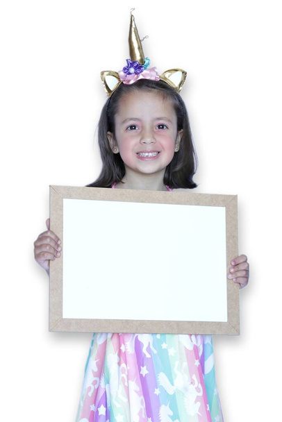 Παιδί σε κοστούμι μονόκερου κρατώντας λευκό πίνακα και λευκό φόντο. - Φωτογραφία, εικόνα