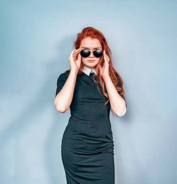 Stylish woman holds black glasses with hands. Black strict dress with a white collar. Sunglasses - Foto, immagini