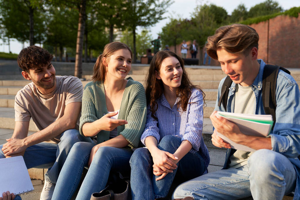 Grupo de estudiantes caucásicos sentados fuera del campus universitario  - Foto, imagen