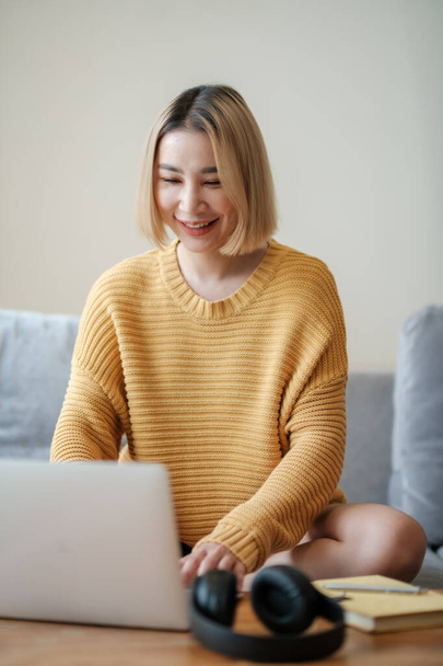 Linda mulher asiática on-line aprendendo com laptop na sala de estar. Foto de alta qualidade - Foto, Imagem
