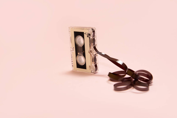 Audio cassette met tape getrokken op een roze achtergrond - Foto, afbeelding