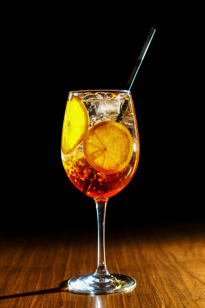 Ένα δροσιστικό κοκτέιλ εσπεριδοειδών και αποσταγμάτων σερβιρισμένο σε ψηλό ποτήρι κρασιού πάνω από πάγο. - Φωτογραφία, εικόνα
