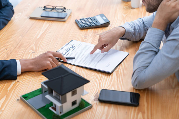 Le client et l'agent immobilier examinent le contrat de prêt, discutent de la durée, du taux d'intérêt et de la propriété. Analyser le document juridique et lire attentivement l'accord avant de prendre une décision. Entité - Photo, image