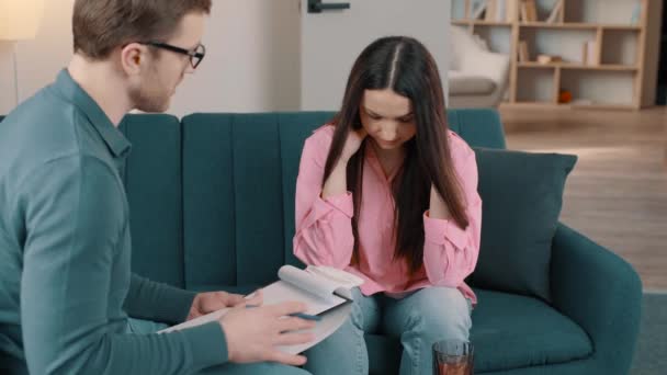 Αρσενικός ψυχολόγος σημειώνει κατά τη διάρκεια συνεδρίας θεραπείας με λυπημένη γυναίκα. Ψυχολόγος και γυναίκα Μιλώντας κάθεται στο σύγχρονο βιομηχανικό χώρο γραφείων - Πλάνα, βίντεο