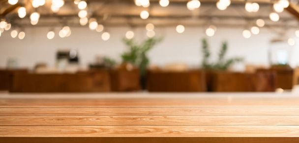 Holztisch im verschwommenen Hintergrund eines modernen Restaurants oder Cafés mit leerem Kopierraum auf dem Tisch für Produktdisplay-Attrappen. Innenraum Restaurant Theke Design-Konzept. - Foto, Bild