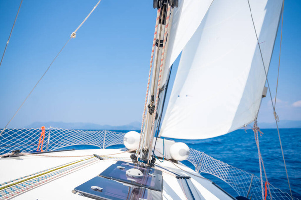 Yacht sailing in an open sea. Close-up view of the deck, mast and sails. Clear sky, waves and water splashes. High quality photo - Photo, Image