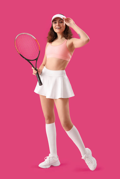 Молодая женщина с теннисной ракеткой на розовом фоне - Фото, изображение