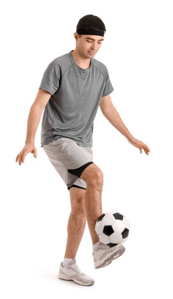 Αθλητικός νεαρός που παίζει με μπάλα ποδοσφαίρου σε λευκό φόντο. Έννοια ισορροπίας - Φωτογραφία, εικόνα