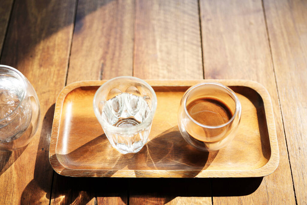 Kuuma kahvi ja lasi jäätä puutarjottimella auringonvalossa - Valokuva, kuva