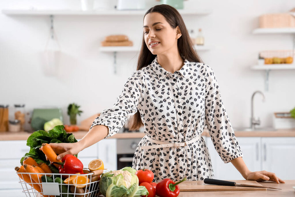 Молодая женщина со свежими овощами на кухне - Фото, изображение