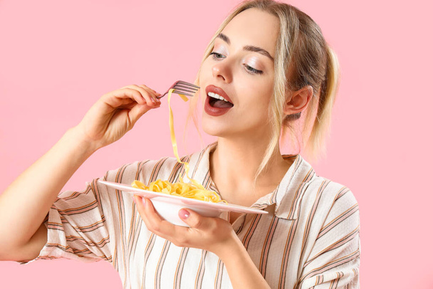 Young woman eating tasty pasta on pink background, closeup - 写真・画像
