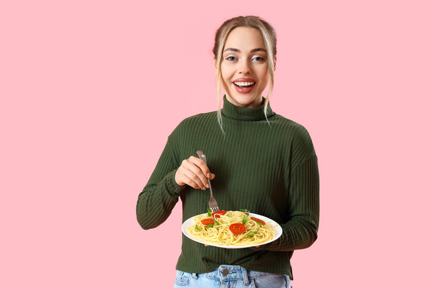 Young woman with tasty pasta on pink background - Фото, изображение