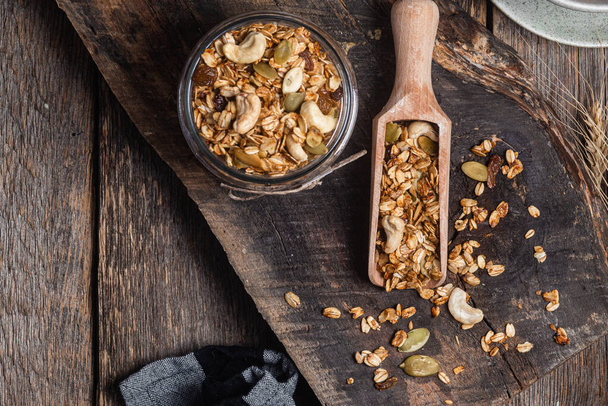 Granola with nuts, raisins and pumpkin seeds in a glass jar - 写真・画像