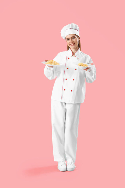 Vrouwelijke chef-kok met borden smakelijke pasta op roze achtergrond - Foto, afbeelding