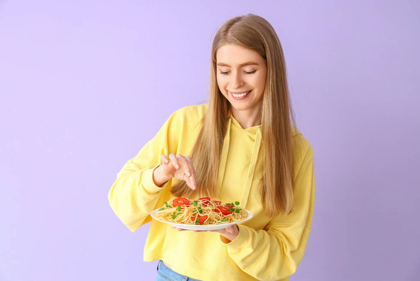 Young woman with tasty pasta on lilac background - Foto, Imagem