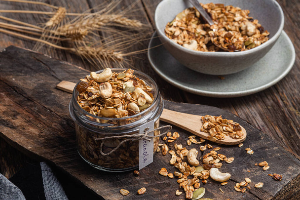 Granola with nuts, raisins and pumpkin seeds in a glass jar - Fotoğraf, Görsel
