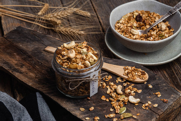 Granola with nuts, raisins and pumpkin seeds in a glass jar - Фото, изображение