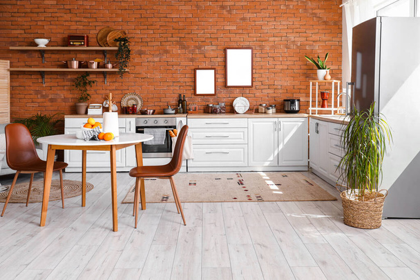 Интерьер кухни со стильным холодильником, прилавками, полками, столом и стульями - Фото, изображение