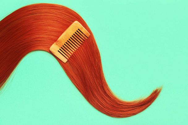 Hermoso cabello de jengibre con peine sobre fondo de color - Foto, imagen