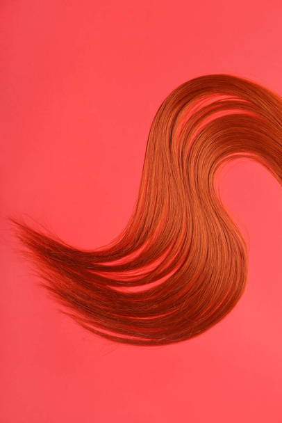 Filo di capelli rossicci su sfondo rosso, primo piano - Foto, immagini