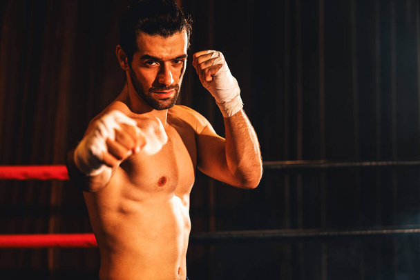 Boxkämpfer ohne Hemd posiert, kaukasischer Boxer schlägt seine nackte Faust und wickelt sich vor der Kamera, aggressive Haltung und bereit, im Boxring zu kämpfen. Impulse - Foto, Bild