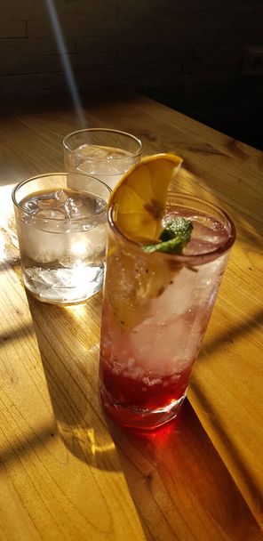 Verres transparents avec boissons sucrées à l'intérieur avec boisson colorée, avec ombre et fond de table avec glaçons sur un bar restaurant - Photo, image