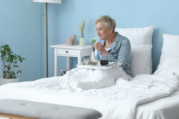 Femme mûre prenant le petit déjeuner au lit
 - Photo, image