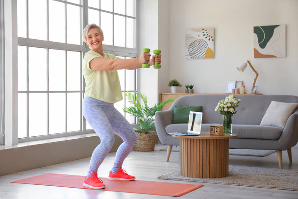 sportliche reife Frau trainiert zu Hause mit Kurzhanteln - Foto, Bild