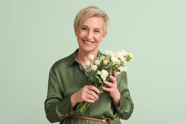 Mature woman with beautiful roses on green background - Foto, imagen