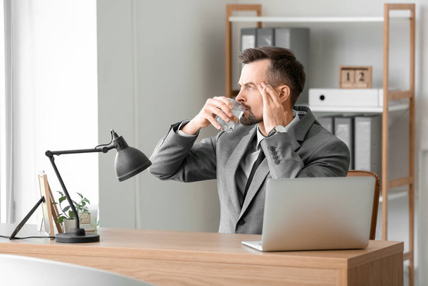 Jovem empresário bebendo água com comprimido dissolvido no escritório - Foto, Imagem