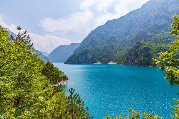 Landscape view of big lake between mountains at summer day. Travel background image with Piva lake in Montenegro - Zdjęcie, obraz
