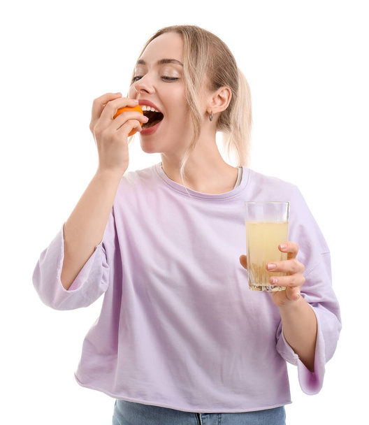 Giovane donna con compressa dissolta in vetro di acqua mangiare arancione su sfondo bianco - Foto, immagini