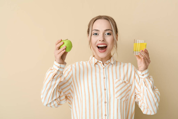 Jonge vrouw met opgeloste tablet in glas water en appel op beige achtergrond - Foto, afbeelding